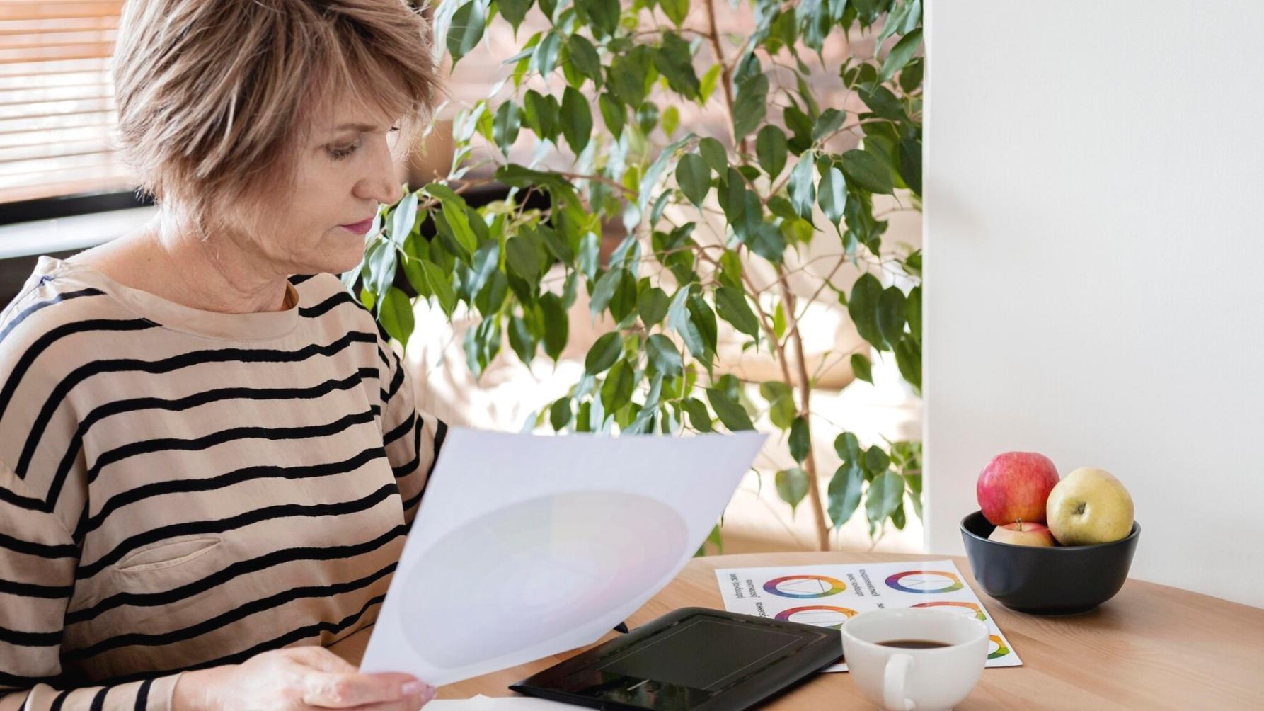 Person arbeitet konzentriert am Laptop mit Finanzunterlagen